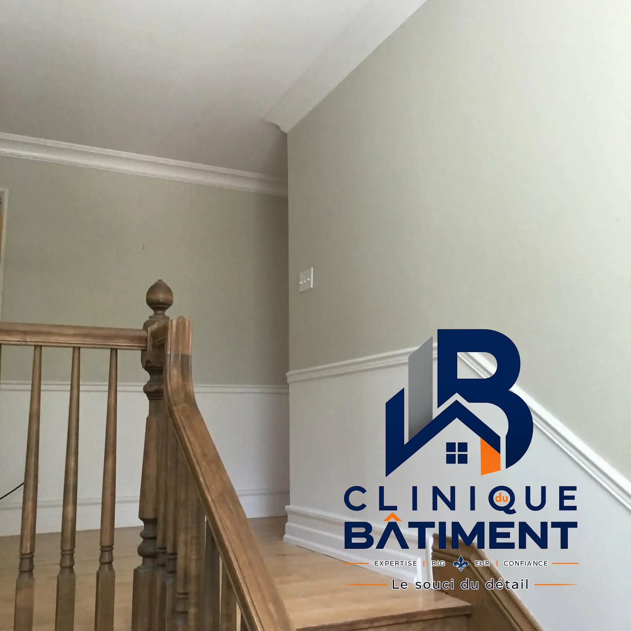 Une cage d'escalier récemment rénovée avec des murs bicolores et des boiseries propres. Réalisation de rénovation à Boucherville — Clinique du Bâtiment (RBQ 5821-2606-01).